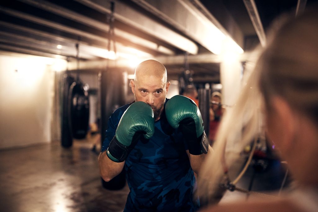 Medlem træner boksning med grønne handsker i Heat Boxing Gym